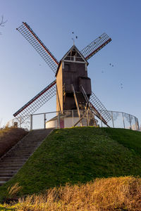 Traditional windmill on field against clear sky