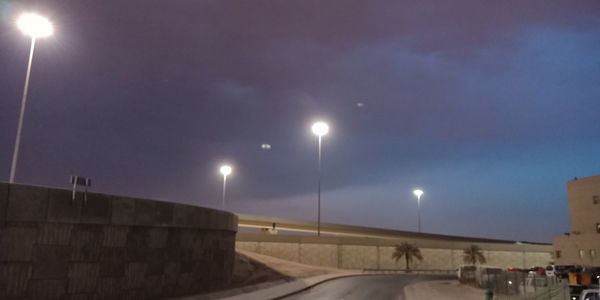 Illuminated street lights against sky at night