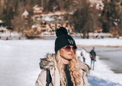 Stylish woman with blond hair, wearing winter clothes, standing on shore of lake jasna in slovenia
