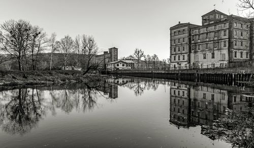 Reflection of buildings and trees in lake against sky