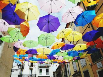 Low angle view of colorful umbrellas amidst buildings in city
