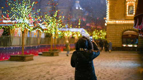 Woman with umbrella on street in city at night