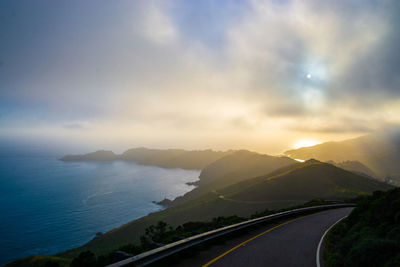 Road by mountains against sky during sunset