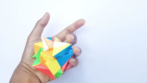 Midsection of person holding multi colored paper over white background