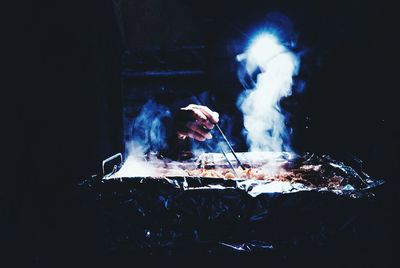 Young woman with fire on barbecue at night