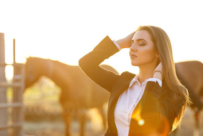 Portrait of young woman standing against clear sky