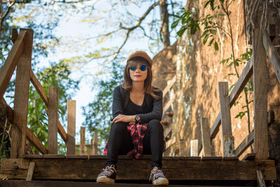 Full length portrait of young woman sitting outdoors