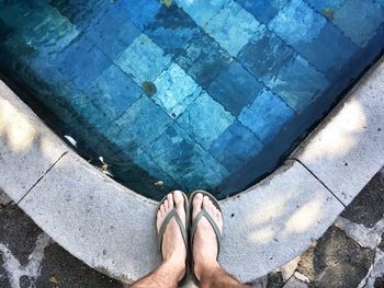 Low section of man standing by swimming pool