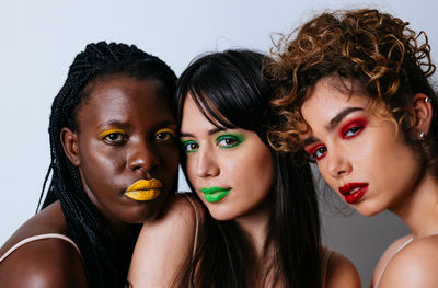 Close-up portrait of women standing against white background