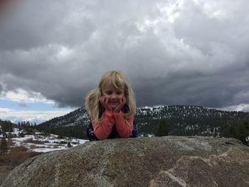 Portrait of happy girl standing on mountain against sky