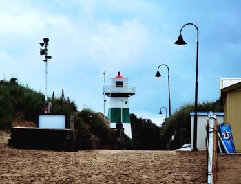 Street lights on beach by buildings against sky