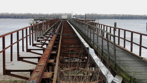 Footbridge over lake against sky