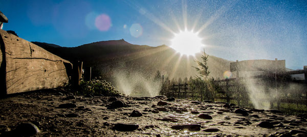 Sun shining over landscape against sky