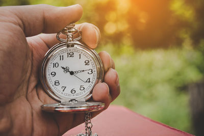 Close-up of hand holding pocket watch outdoors