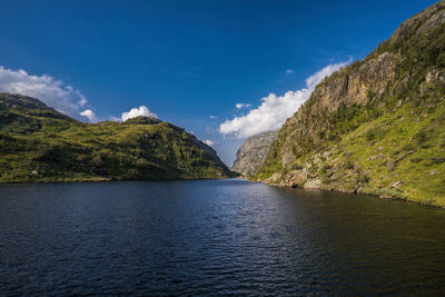 Scenic view of river amidst mountains against blue sky