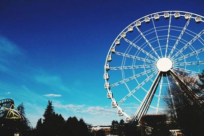 Low angle view of ferris wheel against blue sky