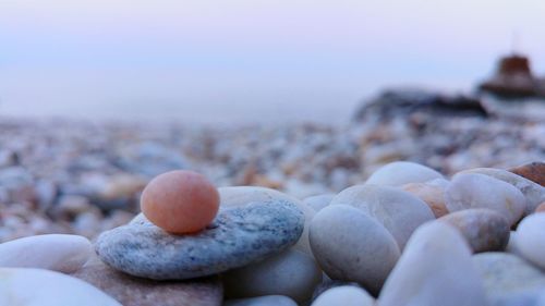 Close-up of hand holding pebbles at beach against sky