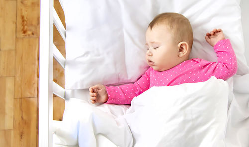 Baby girl sleeping in crib at home