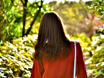 Rear view of woman standing against trees