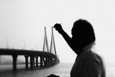 Man holding paintbrush on bridge against sky