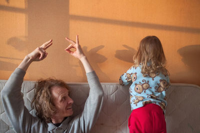 Portrait of girl with arms raised against wall