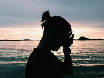 Rear view of woman at sea shore against sky