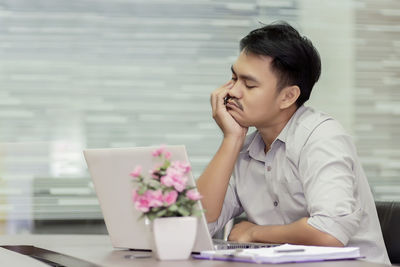 Mid adult man using mobile phone while sitting on table