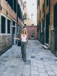 Full length of woman standing on footpath amidst buildings