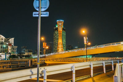 Illuminated street lights by buildings against sky at night