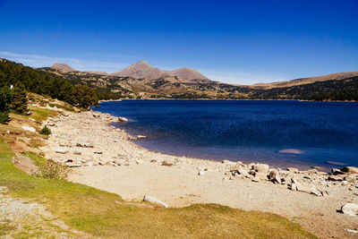 Scenic view of sea and mountains against blue sky