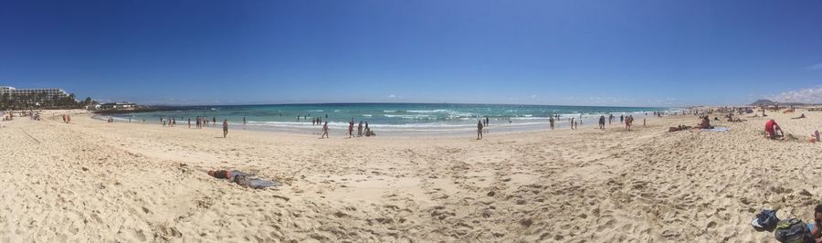 Panoramic view of people on beach against clear sky