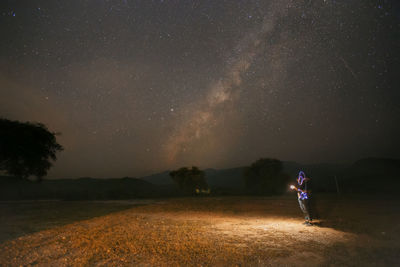 Man standing on field against sky at night