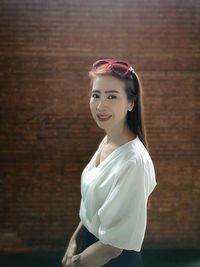 Portrait of smiling young woman against wall