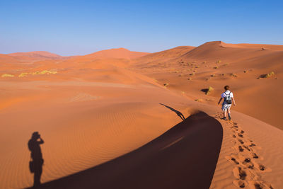 Rear view of woman walking in desert