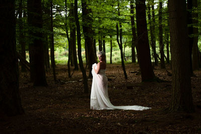 Woman standing on tree trunk in forest