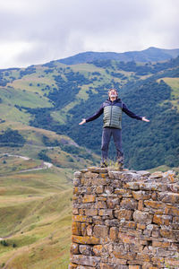 Rear view of man standing on mountain against sky