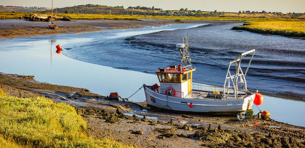 Boat moored on beach against sky