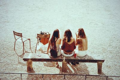 High angle view of women sitting on bench during sunny day