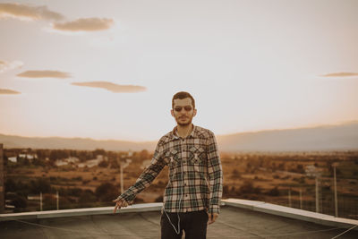 Man standing on terrace against sky during sunset