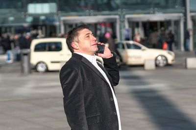 Businessman talking on phone while standing on city street