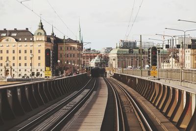 Railroad tracks in city against sky