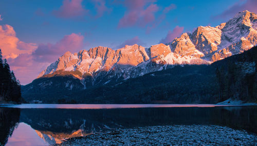 Scenic view of lake by mountains against sky during sunset