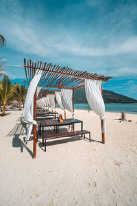 Deck chairs on beach against sky