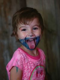 Portrait of cute girl with face paint sticking out tongue