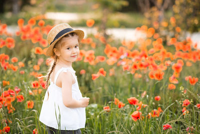 Portrait of cheerful girl wearing hat on flowering field