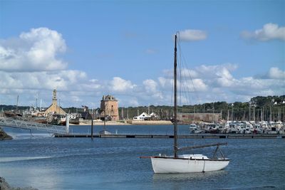 Sailboats moored on sea against sky in city