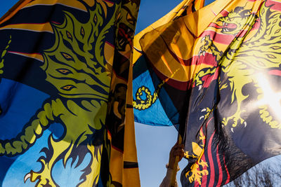 Low angle view of yellow flags against blue sky