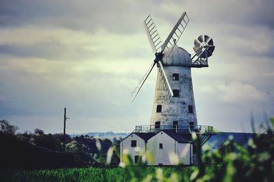 Traditional windmill on field against sky