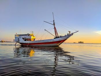 Sailboat sailing in sea against sky during sunset