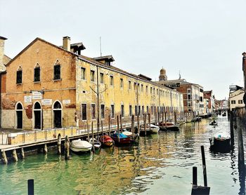 Boats moored in canal against buildings in city